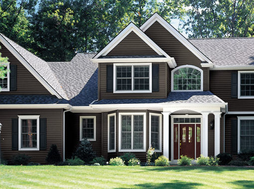 A beautiful suburban home with dark brown siding and a bay window