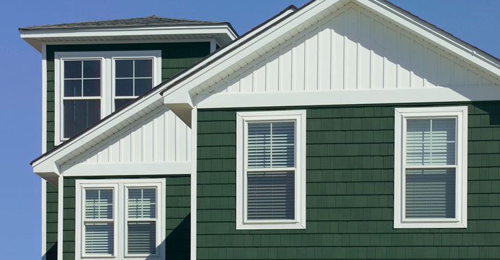 The upper level of a suburban home with green and white siding