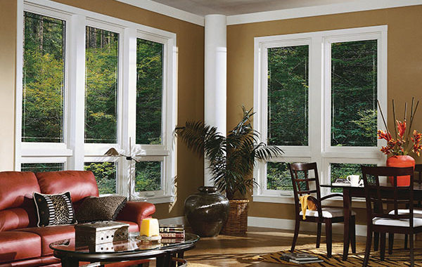 The living and dining area of a home with walls of large windows with white frames